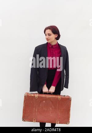 Fille dans un chandail rouge, veste noire avec une valise Banque D'Images