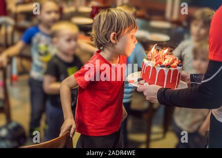 Le temps de souffler les bougies à l'anniversaire d'un enfant. 6 ans souffle les bougies sur un gâteau Banque D'Images