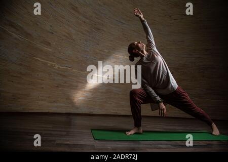 Jeune femme debout dans yoga pose sur le tapis vert Banque D'Images