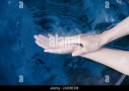 Une paire de mains femme élégante en argile séchée dans l'eau bleue Banque D'Images