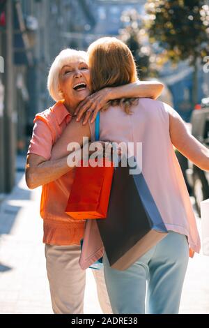 Joyful woman hugging daughter and smiling stock photo Banque D'Images