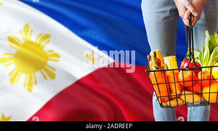 Woman is holding supermarché panier, Philippines waving flag background. Concept de l'économie pour les fruits et légumes. Banque D'Images