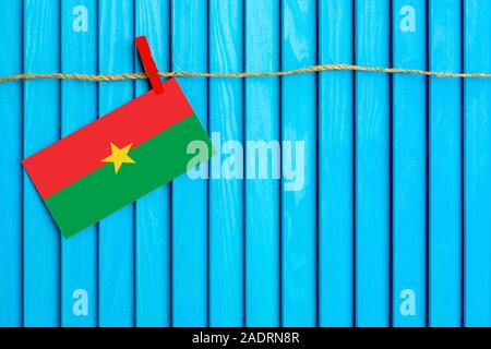 Pavillon de l'Burkina Faso hanging on clothesline attaché avec du linge sur aqua bleu fond de bois. Journée nationale concept. Banque D'Images