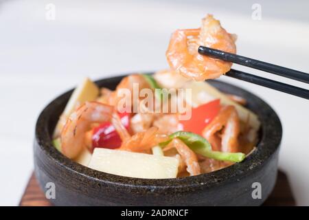 Sauté de crevettes dans un wok avec les assiettes de service dans l'arrière-plan Banque D'Images