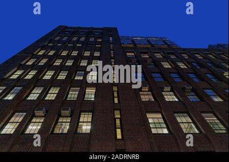 À la recherche jusqu'à la façade d'un grand bâtiment en brique, sur l'Upper East Side de Manhattan de nuit, New York City Banque D'Images