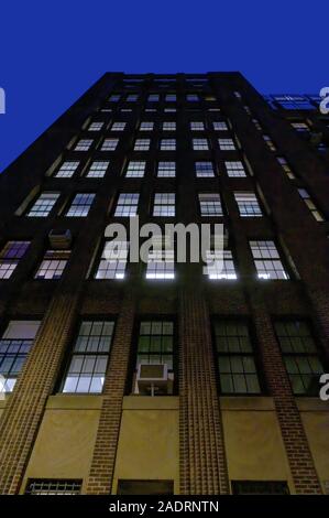 À la recherche jusqu'à la façade d'un grand bâtiment en brique, sur l'Upper East Side de Manhattan de nuit, New York City Banque D'Images