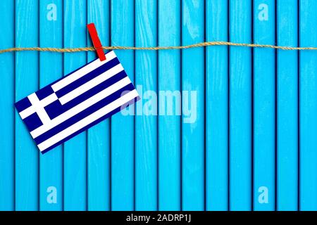 Drapeau de la Grèce hanging on clothesline attaché avec du linge sur aqua bleu fond de bois. Journée nationale concept. Banque D'Images