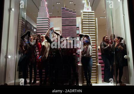 New York, États-Unis. 9Th Jul 2019. Un groupe de personnes de prendre des photos de l'intérieur d'une fenêtre d'affichage kate spade new york au magasin avant l'arbre de Noël les feux sont allumés pour la première fois à la 87e Cérémonie annuelle d'illumination de l'arbre de Noël du Rockefeller Center à New York le Mercredi, Décembre 4, 2019. Photo de John Angelillo/UPI UPI : Crédit/Alamy Live News Banque D'Images