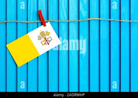 Pavillon de l'Vatican hanging on clothesline attaché avec du linge sur aqua bleu fond de bois. Journée nationale concept. Banque D'Images