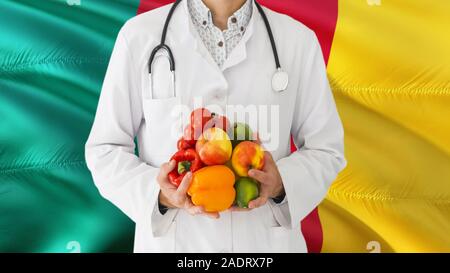 Médecin est maintenant les fruits et légumes dans les mains à l'arrière-plan du pavillon du Cameroun. Concept national de santé, médicaux thème. Banque D'Images