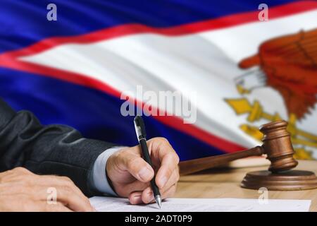 Le juge écrit sur papier dans la salle d'audience avec le drapeau des Samoa américaines. Wooden gavel d'égalité thème et concept juridique. Banque D'Images