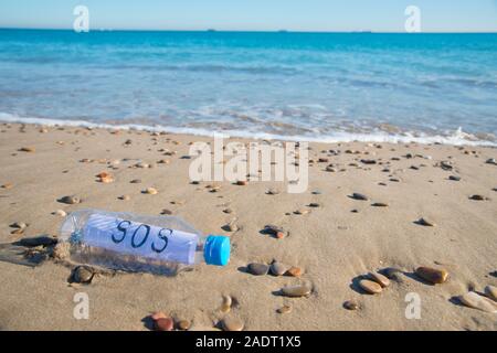 La contamination en plastique de la mer. Message SOS dans une bouteille en plastique au bord de la mer. Banque D'Images