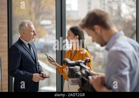 Asian female reporter la tenue d'un microphone et souriant Banque D'Images