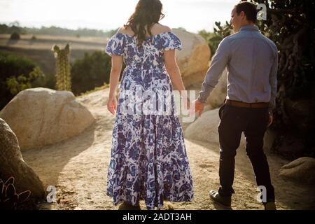 Mari et femme enceinte dans jardin de cactus marche loin Banque D'Images
