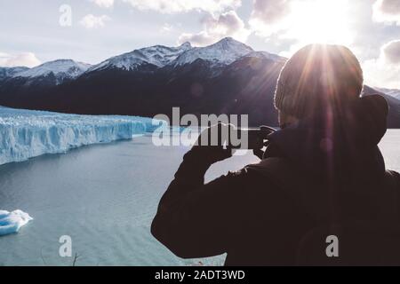 Meilleur mâle de la prise d'une photo avec un mobile près de glacier par jour nuageux Banque D'Images