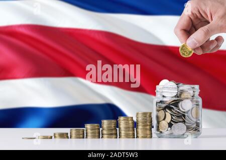 Business man holding coins mise en verre, de brandir le drapeau du Costa Rica dans l'arrière-plan. Concept de la finance et des affaires. L'économie d'argent. Banque D'Images