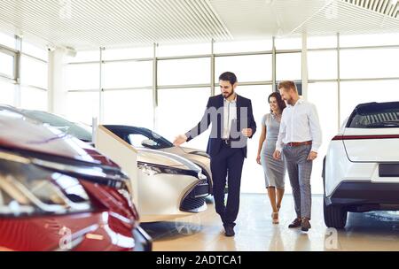 Couple et le concessionnaire vente de voitures chercher la voiture dans le showroom. Banque D'Images