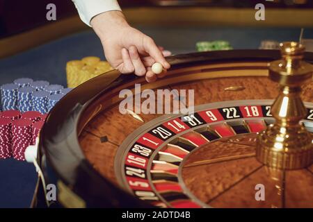 Main d'un casino avec une balle sur une roulette au cours d'une partie dans un casino. Banque D'Images