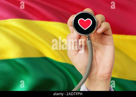 Doctor holding stethoscope avec amour rouge coeur. Drapeau national de Bolivie l'arrière-plan. Système de soins médicaux, concept thème. Banque D'Images