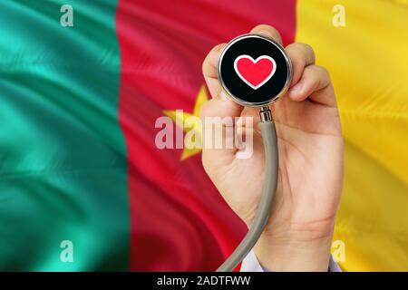 Doctor holding stethoscope avec amour rouge coeur. Drapeau national du Cameroun. Système de soins médicaux, concept thème. Banque D'Images