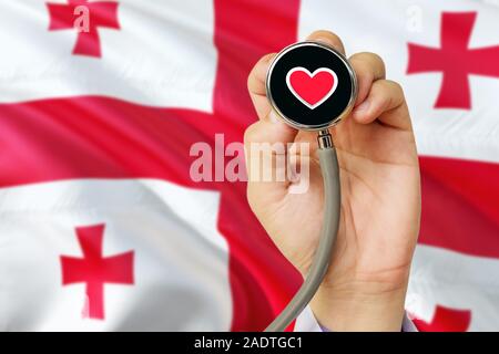 Doctor holding stethoscope avec amour rouge coeur. Drapeau national de la Géorgie. Système de soins médicaux, concept thème. Banque D'Images