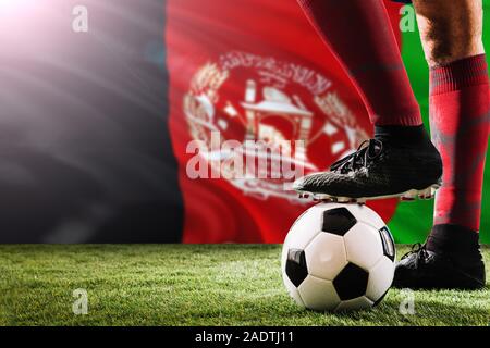 Close up les jambes de l'Afghanistan de l'équipe de football player en rouge chaussettes, chaussures le ballon de soccer au point de penalty ou coup franc jouant sur l'herbe. Banque D'Images