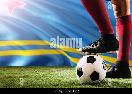 Close up jambes d'Aruba de football player en rouge chaussettes, chaussures le ballon de soccer au point de penalty ou coup franc jouant sur l'herbe. Banque D'Images