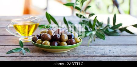 Assortiment d'olives fraîches et d'huile d'olive en verseuse en verre sur fond de bois. Copy space Banque D'Images