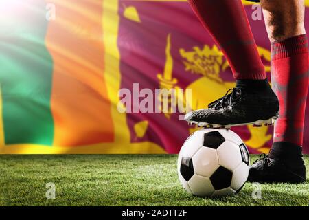 Close up jambes de Sri Lanka l'équipe de football player en rouge chaussettes, chaussures le ballon de soccer au point de penalty ou coup franc jouant sur l'herbe. Banque D'Images