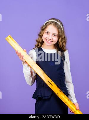 Étude de l'étudiant de l'école de géométrie. Kid l'uniforme scolaire tenir règle. Élève fille mignonne avec grande règle. Sous réserve de l'école de géométrie. L'éducation et de l'école concept. Concept astucieux et intelligent. Le calibrage et la mesure. Banque D'Images