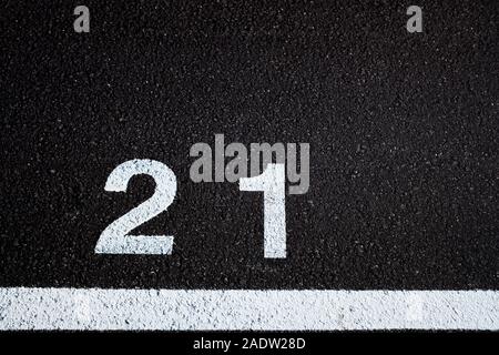 Numéro 21, âge légal, peint sur le sol pavé d'un terrain de stationnement peint en blanc, Banque D'Images