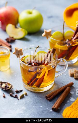 Cidre chaud Apple avec des épices dans la coupe en verre. Fond noir en gris Banque D'Images