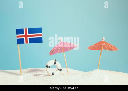 Drapeau de l'Islande en miniature sur plage avec parasols colorés et conservateur de vie. Concept de voyage, thème d'été. Banque D'Images