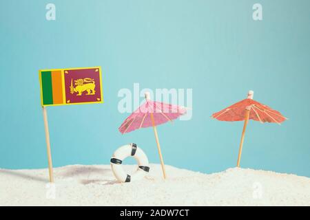 Drapeau Miniature de Sri Lanka sur plage avec parasols colorés et conservateur de vie. Concept de voyage, thème d'été. Banque D'Images