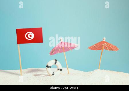 Drapeau de la Tunisie sur Miniature plage avec parasols colorés et conservateur de vie. Concept de voyage, thème d'été. Banque D'Images