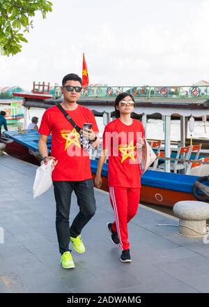 Les touristes portant des T shirts Vietnam rouge correspondant à marcher le long du fleuve Hoi An Vietnam Banque D'Images