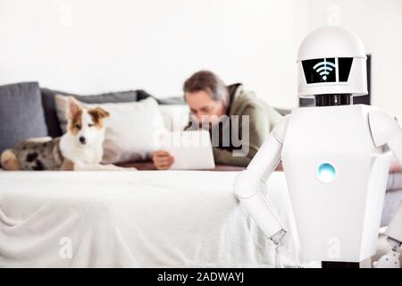 L'homme est allongé sur un canapé avec son chien et chiot utilise sa tablette alors que son service ménage robot est debout à l'avant, un réseau LAN ou wifi symbole sur hi Banque D'Images