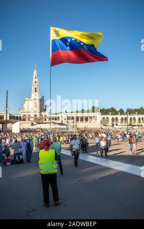 Fatima, Portugal - 12 mai 2019 : Pilgrim avec drapeau du Venezuela palpitations dans le sanctuaire de Fatima, au Portugal, avec la basilique en arrière-plan. Banque D'Images