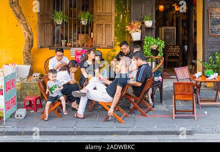 Famille vietnamienne assis sur de petites chaises à l'extérieur de l'atelier à Hoi An, Vietnam Ann Banque D'Images