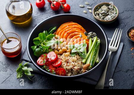 Salade végétarienne saine. Citrouille rôties, quinoa, tomates, salade verte. Bol Bouddha. Fond d'ardoise. Close up. Banque D'Images