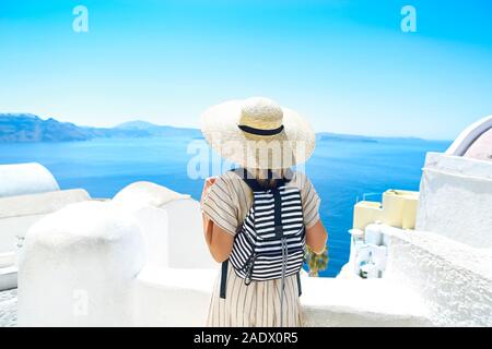 Jeune femme en robe blanche et chapeau de paille, balade dans la ville de Oia, Santorin, Grèce. Concept de loisirs, tourisme, voyages, vacances, r Banque D'Images