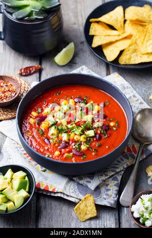 Soupe mexicaine. Tomate, haricot, poivron dans bol noir Banque D'Images