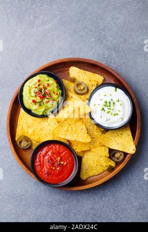 Nachos chips dans un bol avec des sauces, trempette variété. Arrière-plan de pierre grise. Vue d'en haut Banque D'Images