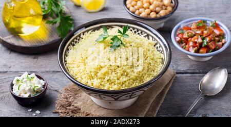 Couscous dans un bol avec l'huile d'olive. Fond de bois. Close up Banque D'Images