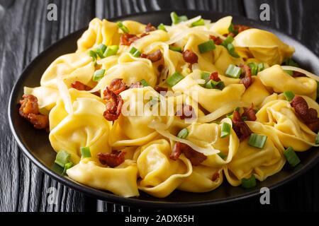 Tortelloni savoureux avec du bacon et fromage close-up dans une assiette sur la table horizontale. Banque D'Images