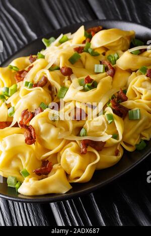 Tortelloni au jambon, fromage et oignons verts close-up dans une assiette sur la table verticale. Banque D'Images