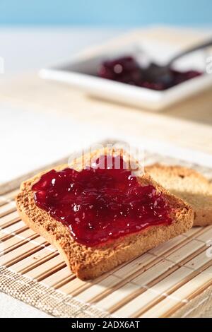 Biscottes avec confiture rouge sur tableau avec fond bleu pâle Banque D'Images