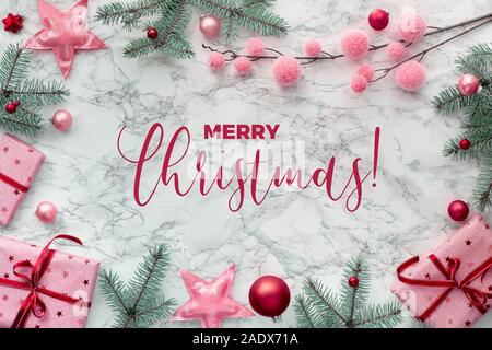 Vue panoramique sur la mise à plat de Noël en blanc avec bordure faite de cadeaux emballés, les brindilles de sapin vert, rouge et rose bibelots. Texte 'Merry Chr Banque D'Images
