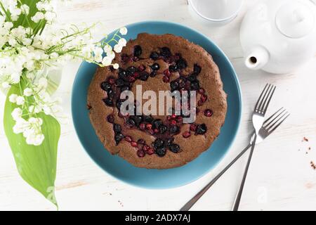 Dessert maison saine. Sibérien traditionnel gâteau avec bird cherry, airelle rouge et cassis servi avec théière blanche et le muguet rose ... Banque D'Images