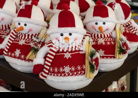 Un jouet bonhomme de neige dans un chandail rouge et un chapeau avec un pompon holding skis en bois et d'une brindille d'un arbre de Noël dans ses mains Banque D'Images